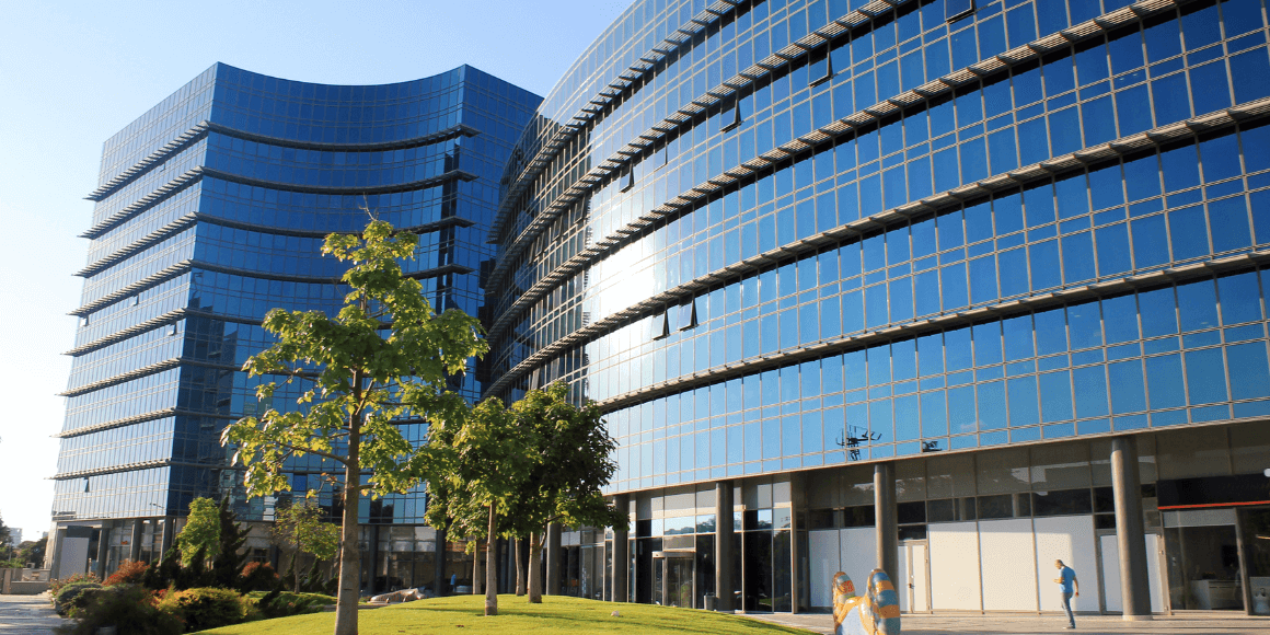 Exterior view of a modern office building with green space in front