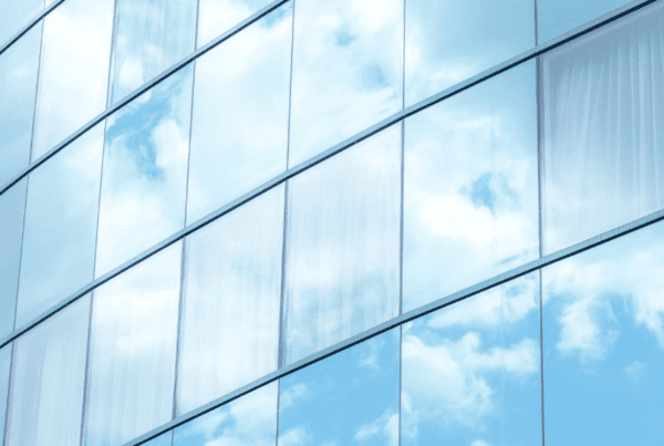 Corporate building with reflective window film mirroring a partially cloudy sky